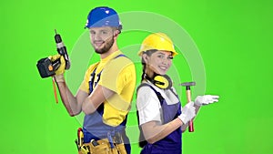 Builder standing a guy holding a drill, a girl hammer. Green screen. Slow motion
