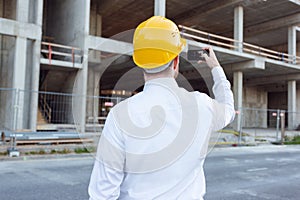 Builder Taking Photos by Phone of Cunstruction Works. Man in Hardhat. House Building