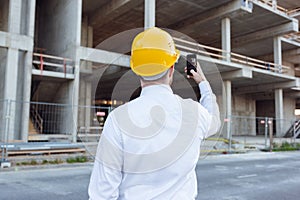 Builder Taking Photos by Phone of Cunstruction Works. Man in Hardhat. House Building