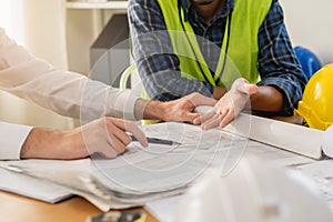 Builder team, hand of asian, caucasian young engineer, architect two man are discussing construction drawing on blueprint follow