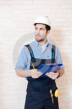 Builder thinking about something and holding a clipboard