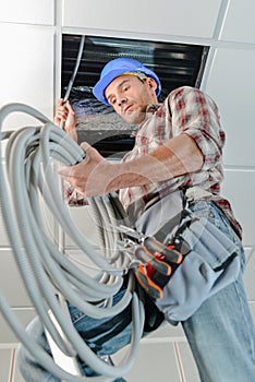 Builder threading cable into roofspace