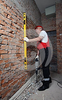 Builder in uniform with level and plugger