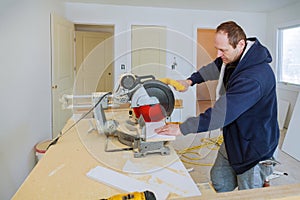 Builder uses circular saw tool to cut wood baseboard woodwork