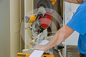 Builder uses portable circular saw tool to cut wood baseboard woodwork