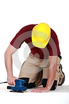 Builder using sander on floor