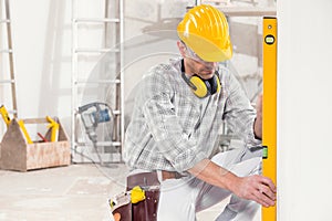 Builder using a spirit level to measure a wall