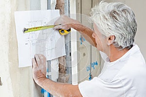 Builder using tape measure to check building plans