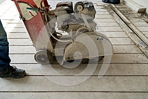 A builder is using a tool to cut concrete into strips to form a parking lot for a car park while it is under construction