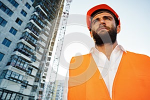 Builder wearing hardhat and safety vest standing on a commercial construction site