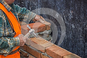 Builder worker with bricklayer hammer laying solid clay brick 2
