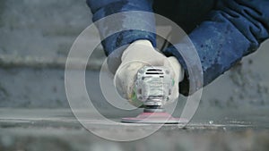 Builder worker with grinder machine cutting finishing concrete wall at construction site. Clip. Worker grinds concrete