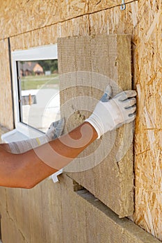 Builder worker installing insulation material on a wall.