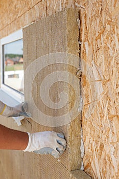Builder worker installing insulation material on a wall.