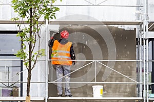 Builder worker painting wall with roller