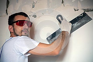 builder worker plastering facade of high-rise building with putty knife