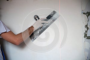 builder worker plastering facade of high-rise building with putty knife