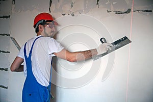 builder worker plastering facade of high-rise building with putty knife