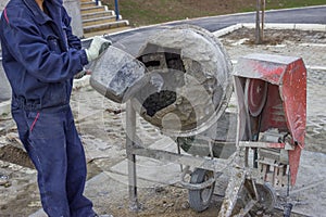 Builder worker putting water in a cement mixer 2