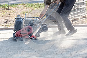 Builder worker at sand ground compaction with vibration plate compactor machine before pavement roadwork.