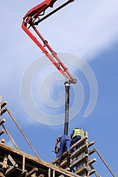 Builder worker with tube from truck mounted concrete pump