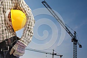 Builder worker in uniform and helmet operating with tower crane