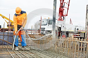 Builder worker vibrating concrete in form