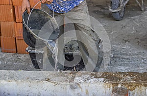 Builder worker wetting concrete with bucket of water 2