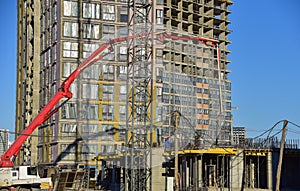 Builder workers during formworks and pouring concrete through a Ñoncrete pump truck connected to a ready-mixed truck. Concrete