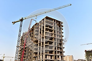 Builder workers during formworks and pouring concrete through a Ñoncrete pump truck connected to a ready-mixed truck. Concrete