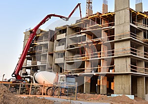 Builder workers during formworks and pouring concrete through a Ñoncrete pump truck connected to a ready-mixed truck. Concrete