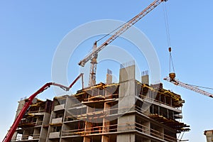 Builder workers during formworks and pouring concrete through a Ñoncrete pump truck connected to a ready-mixed truck. Concrete