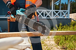 Builder working with chainsaw on wood board