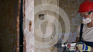 Builder working with rotary hammer drill. Contractor drills holes in concrete with jackhammer to demolish the wall for