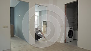 A builder in working uniform checks the size and quality of doorways in a new apartment