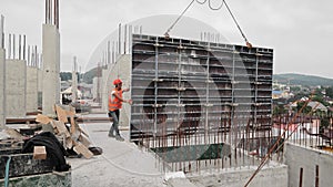 The builder works on the construction site. Installation of a large metal structure on the roof of the building