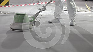 A builder works with an industrial grinder on a concrete floor. Floor grinding at a construction site. concrete floor