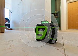 Builder works with a laser construction level in the apartment that is under construction, remodeling, renovation, overhaul,