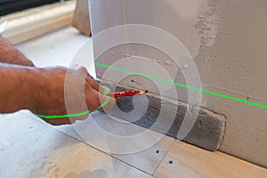 Builder works with a laser construction level in the apartment that is under construction, remodeling, renovation, overhaul,