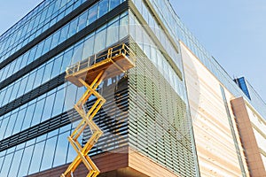 Builders on the air platform during installation of facade glazing. The scissor lift