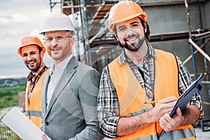 builders and architect with blueprint and clipboard looking