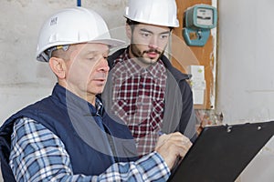 builders with clipboard and electrical panel indoors