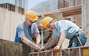 Builders cooperating on cement formwork frames