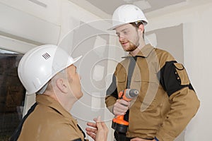 builders in hardhats with electric drill indoors