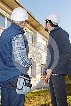 builders in hardhats pointing finger outdoors