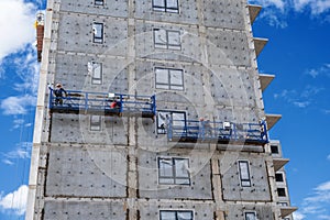 Builders, installers, high-rise workers, industrial climbers, plasterers on the lift, cladding of the facade of the