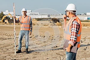 builders in orange vests and helmets working on the road construction field