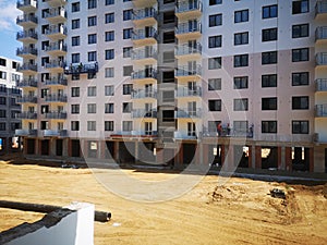 Builders paint the facade of an apartment building. Construction of apartments