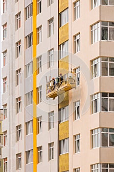 Builders paint the facade of a high-rise residential building