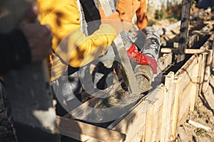 Builders pouring concrete with pump truck in wooden formwork with reinforcement. Workers pouring concrete in formwork for